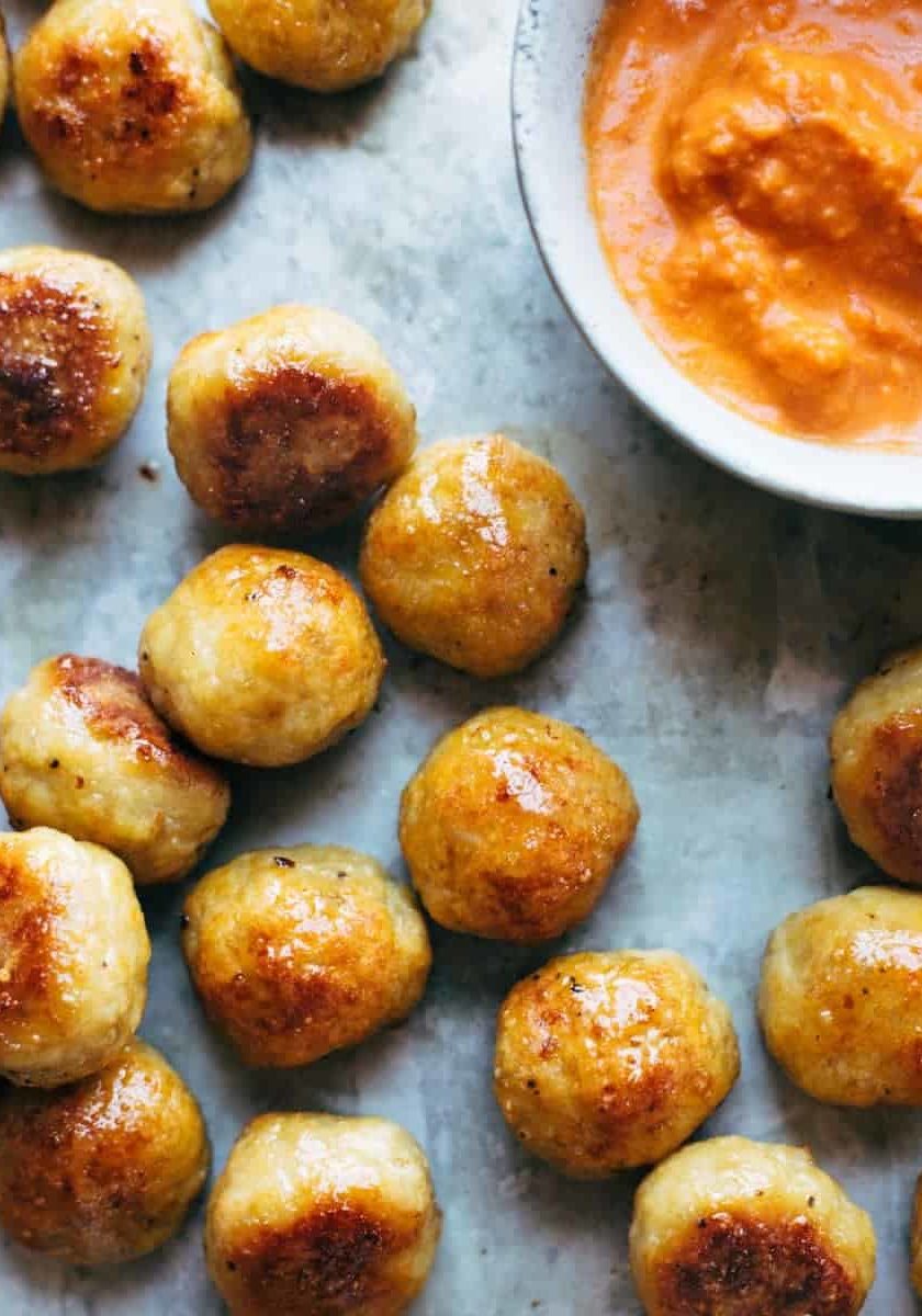 Baked Chicken Meatballs on a sheet pan with sauce.