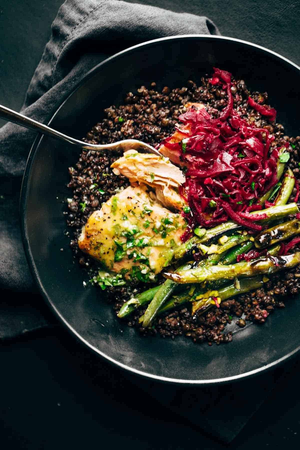 Bowl with salmon and lentils on a napkin with a spoon.