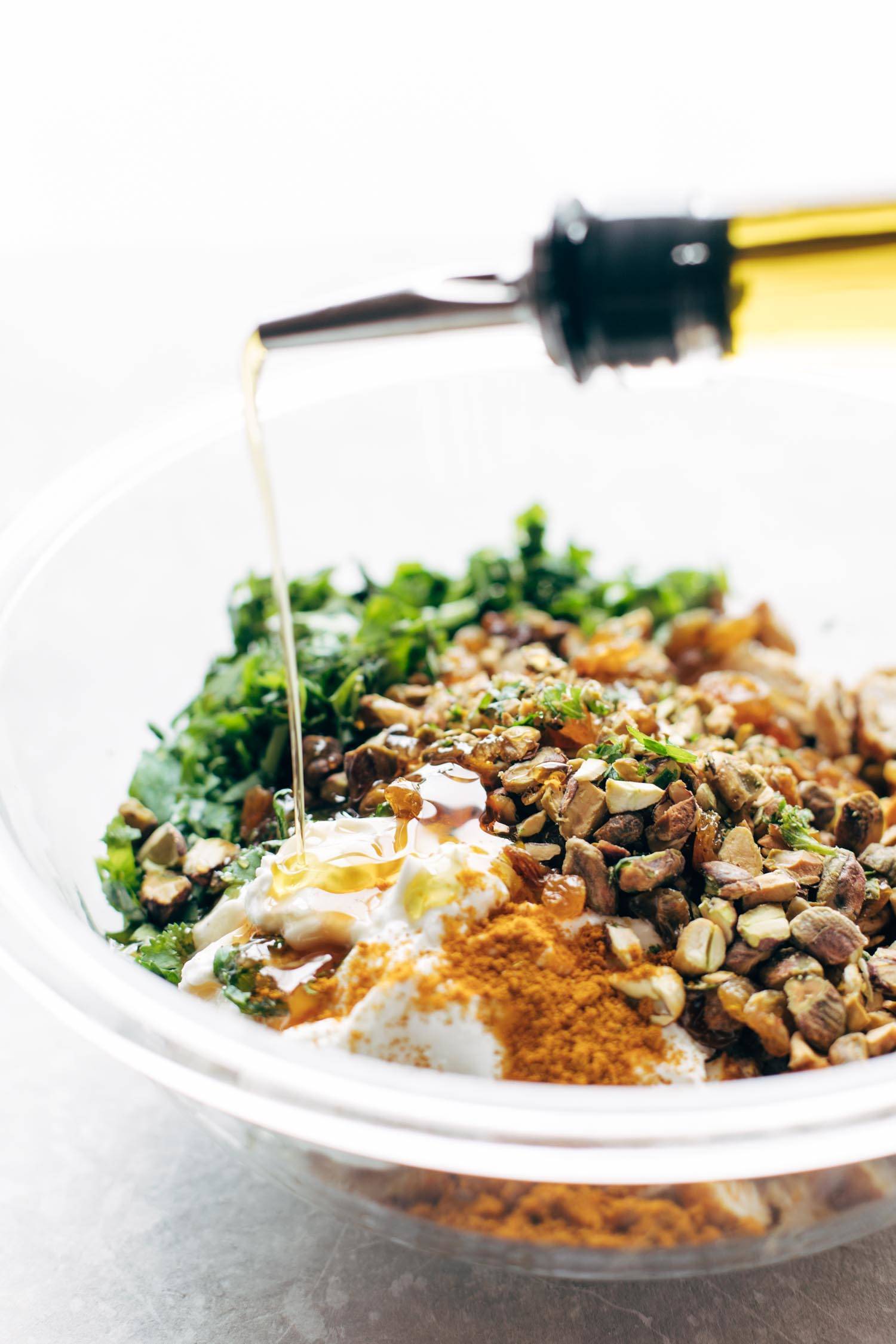 Curry Chicken Salad ingredients in a bowl with oil drizzle.