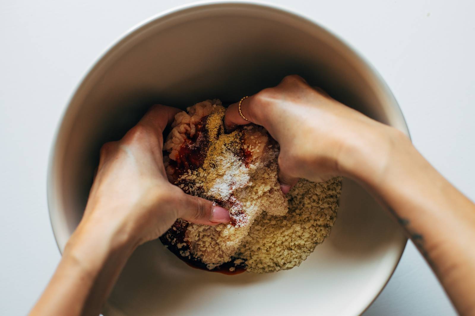 White hands mixing chicken into burgers