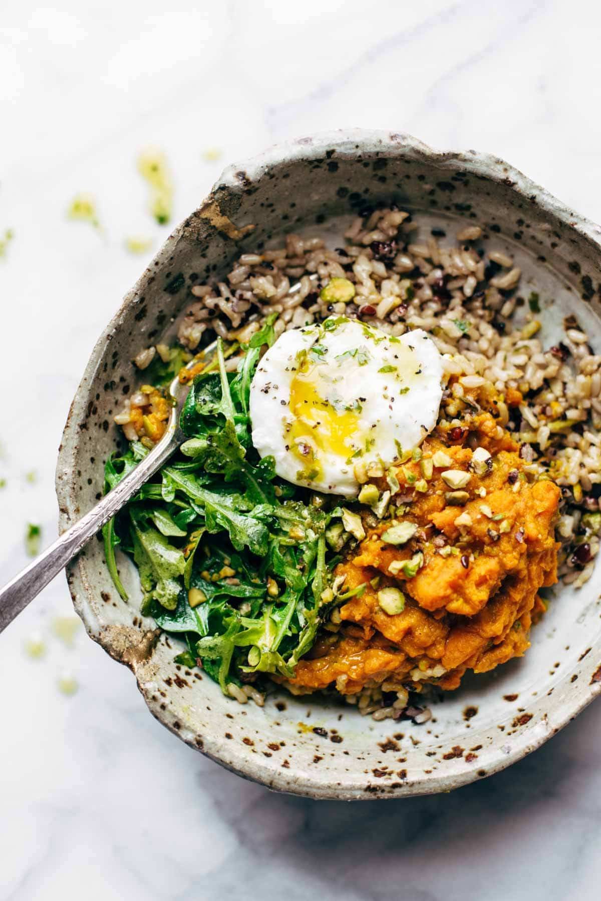 Bowl with sweet potatoes and brown rice with an egg and a fork.