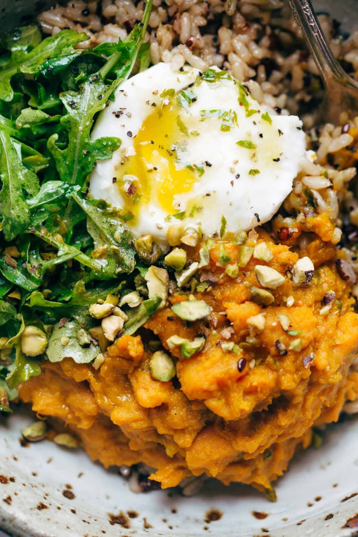 Sweet potatoes with brown rice and an egg in a bowl with a fork.