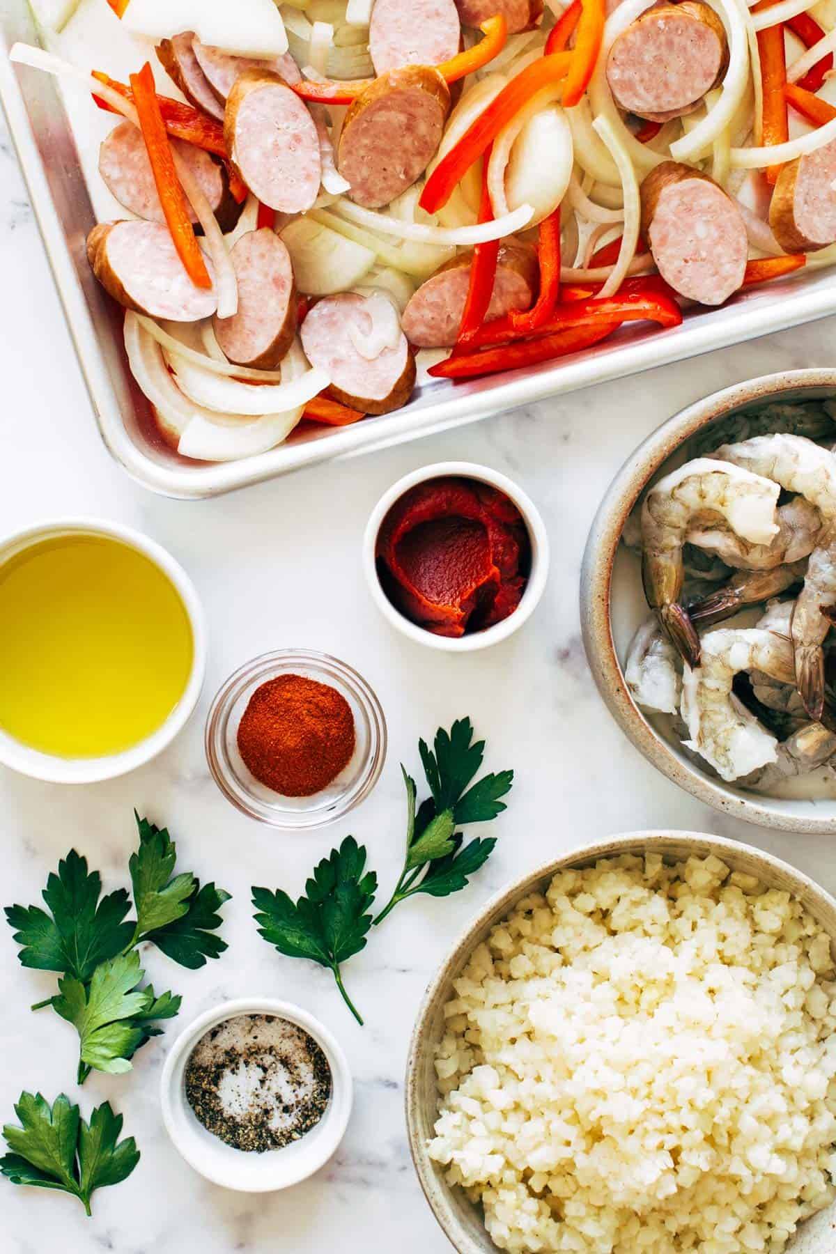 Ingredients for Sheet Pan Jambalaya on a marble countertop.