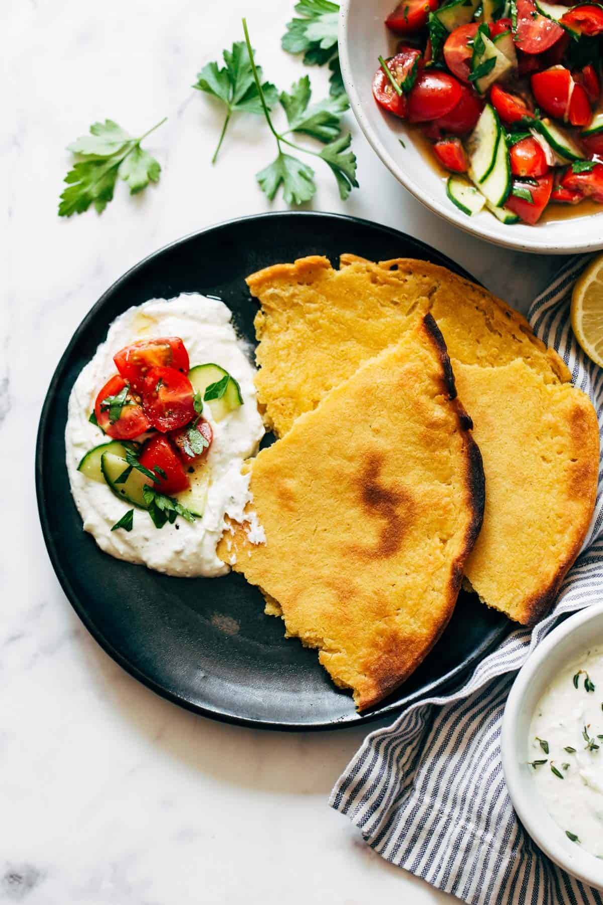 Socca with whipped feta along with tomato salad on the plate.