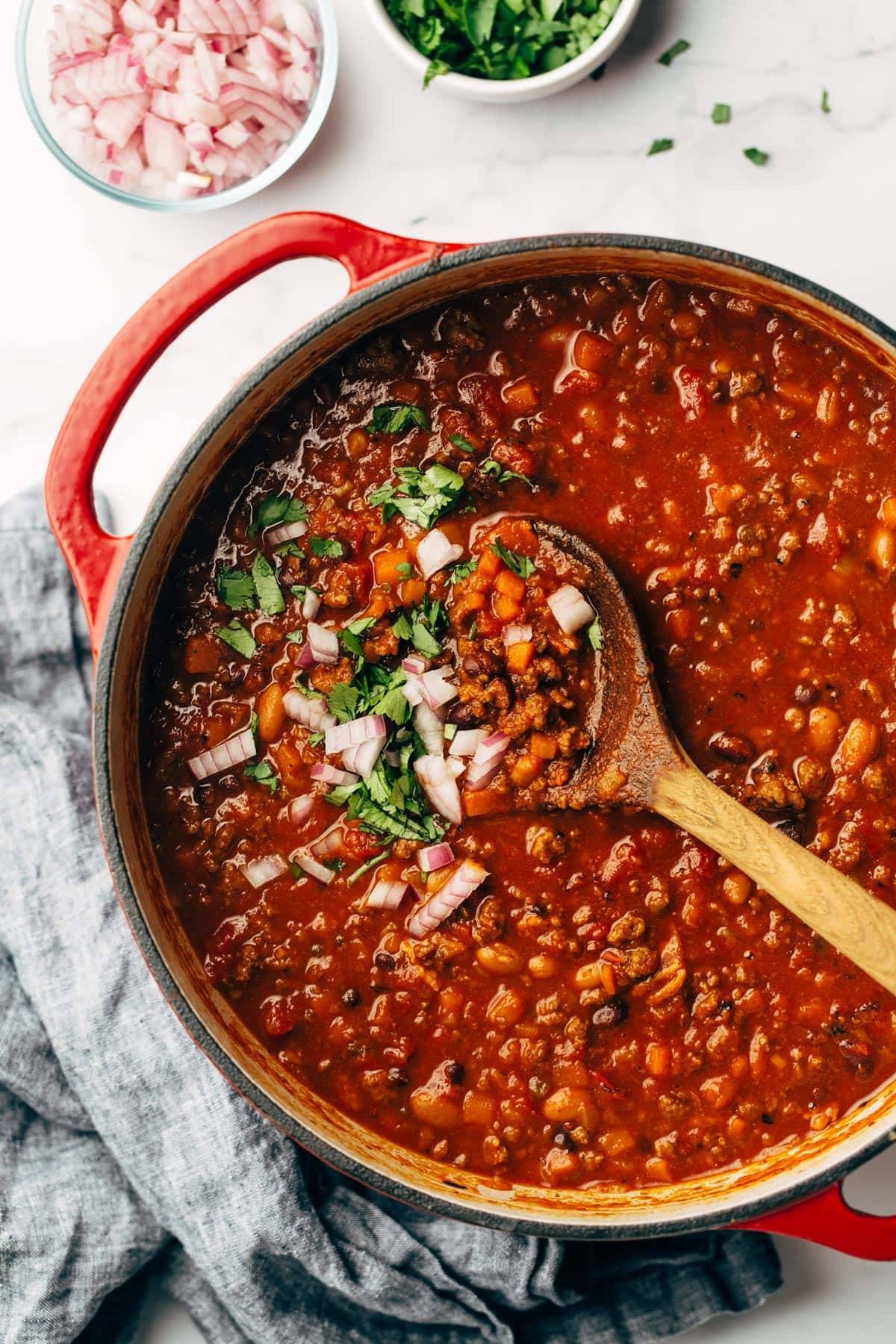 Sunday chili in a dutch oven with a spoon.